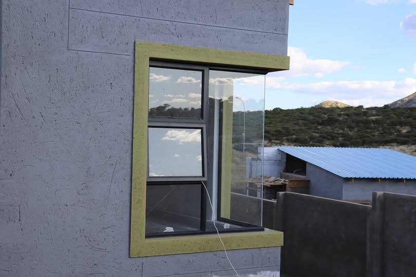 Aluminium window set into an olive-painted wall